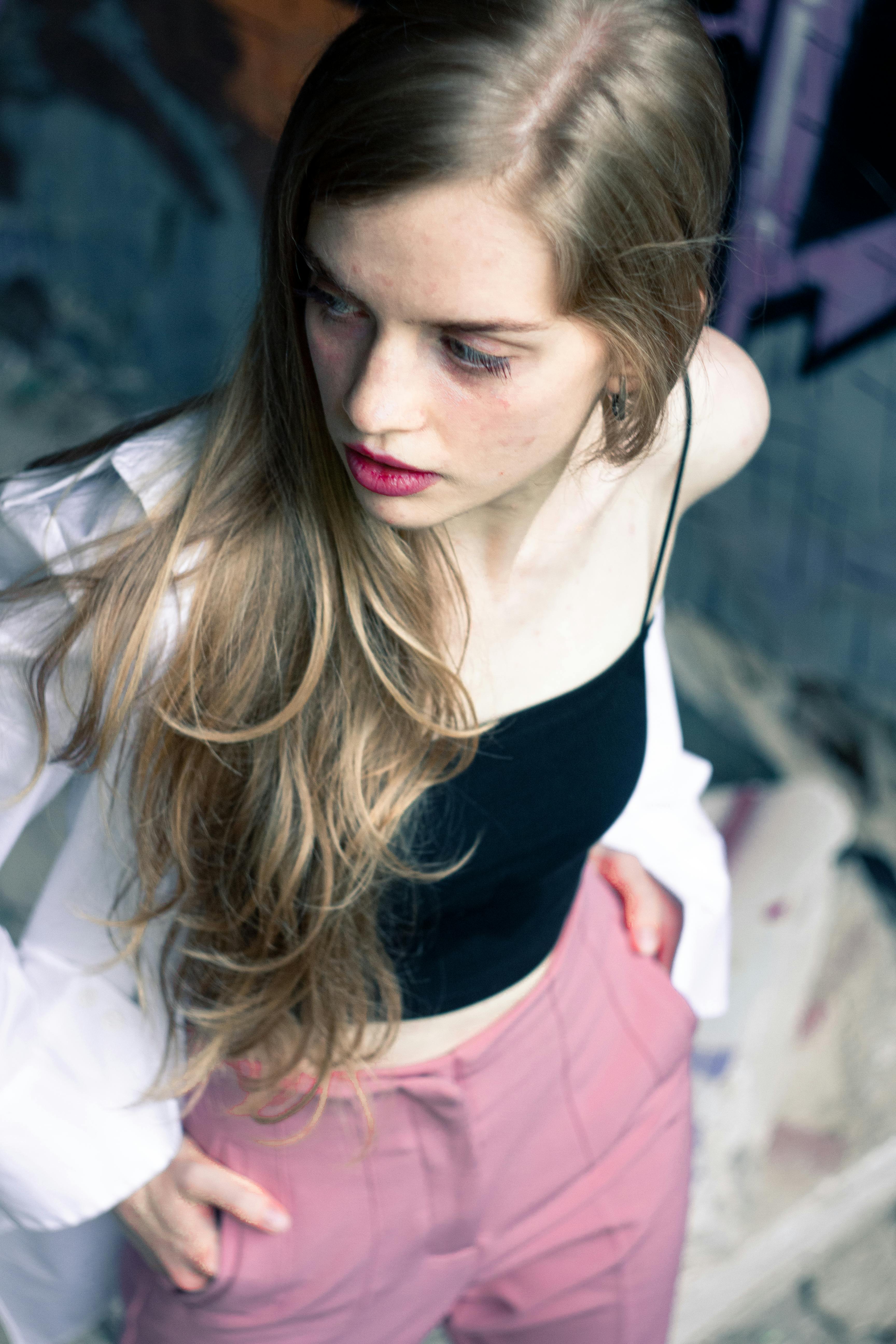 Fashion model poses in an urban setting wearing a black crop top and pink pants.