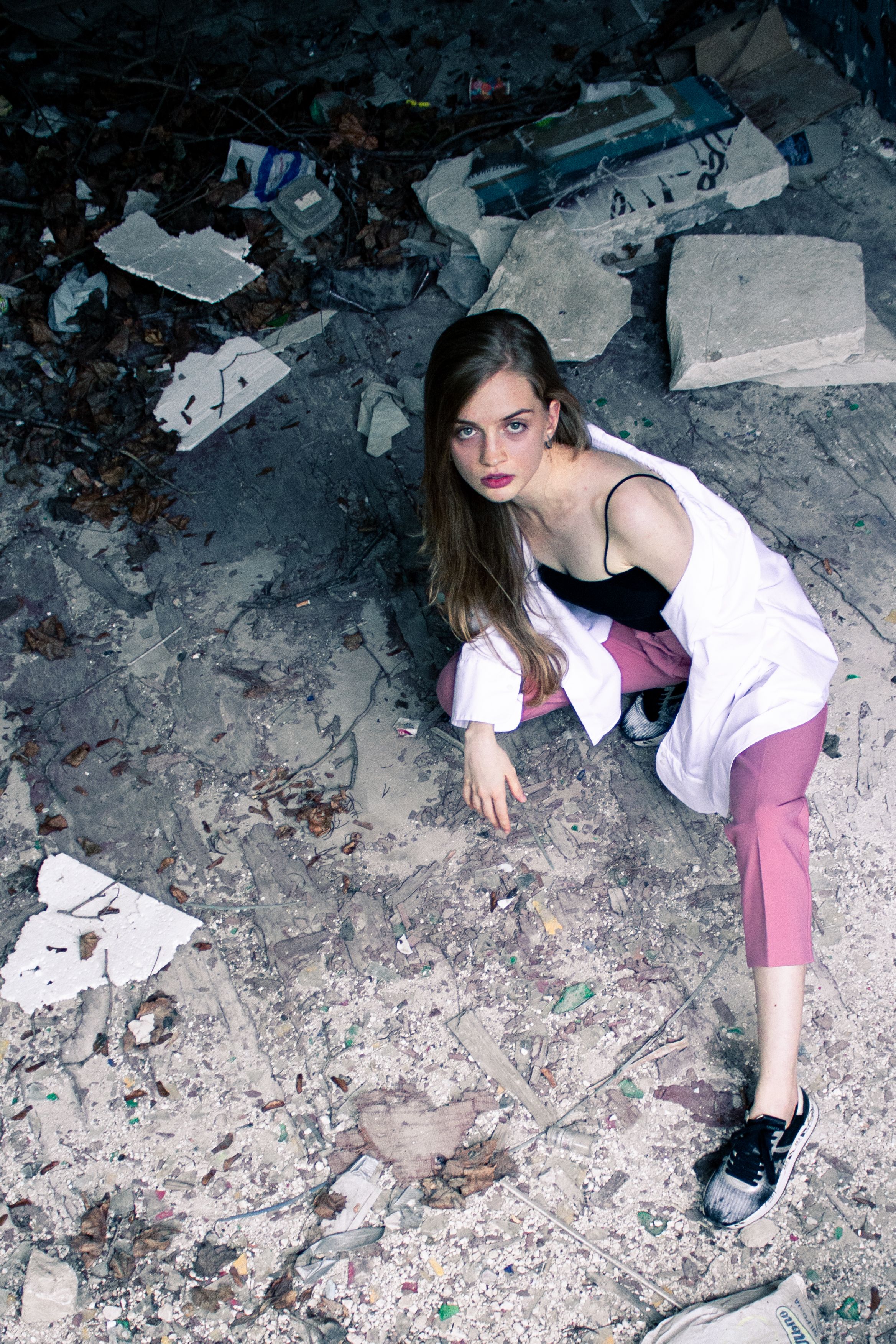 Stylish woman posing among urban ruins, showcasing edgy fashion and attitude.