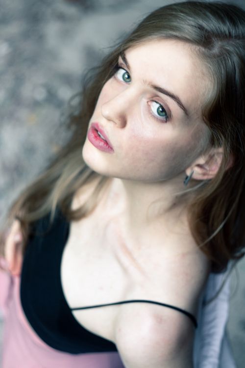 Free Close-up high angle portrait of a young woman with expressive eyes looking upwards, wearing a black top, indoors. Stock Photo
