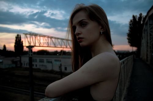 Free A young fashionable woman poses stylishly against a metal railing during sunset. Stock Photo