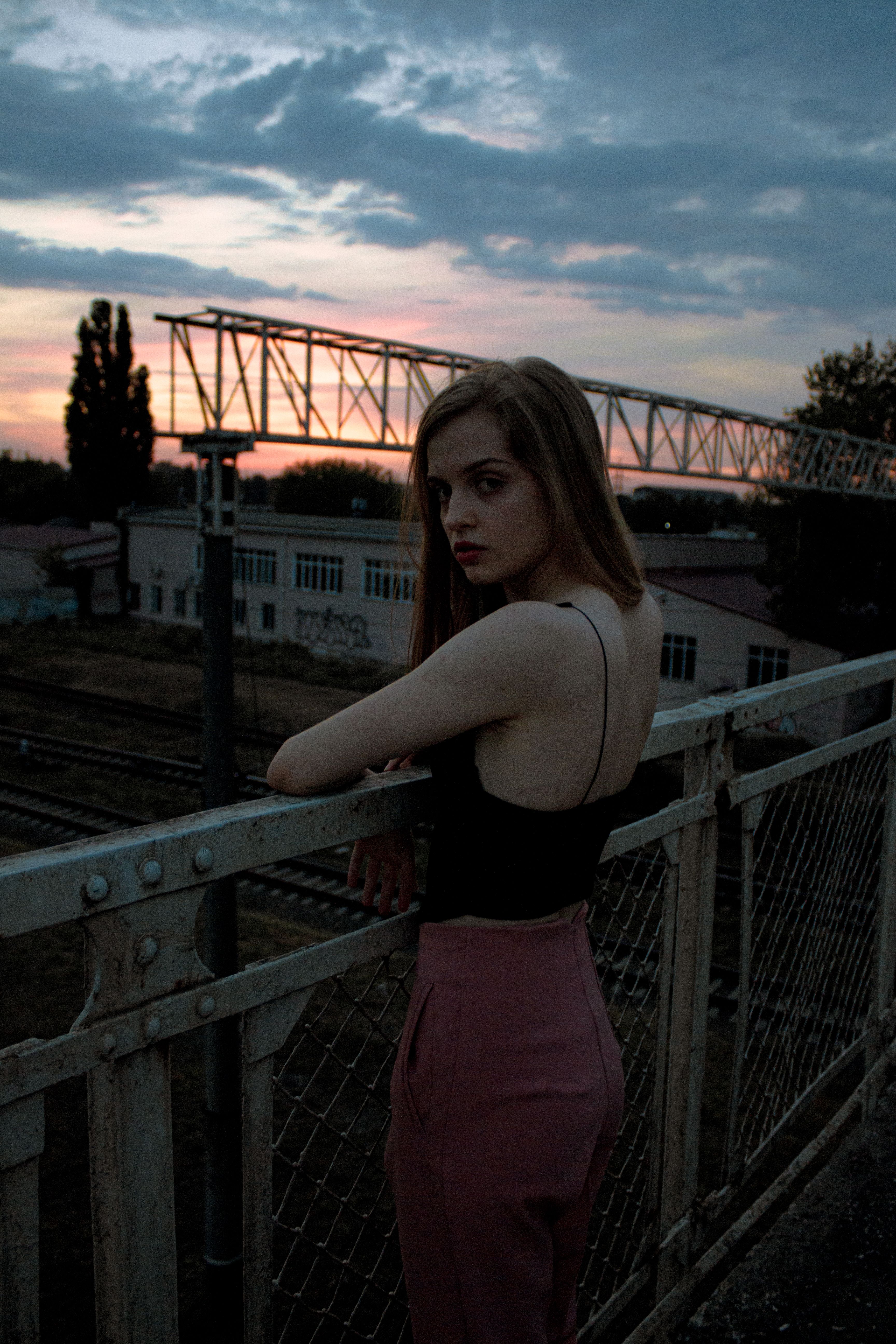 A Young Woman Leaning on Metal Railing · Free Stock Photo