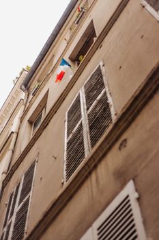 低角度拍摄的法国建筑立面，可见法国国旗和经典的百叶窗