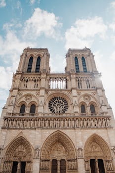 从低视角仰望，巴黎圣母院的哥特式建筑在蓝天下显得格外惊人