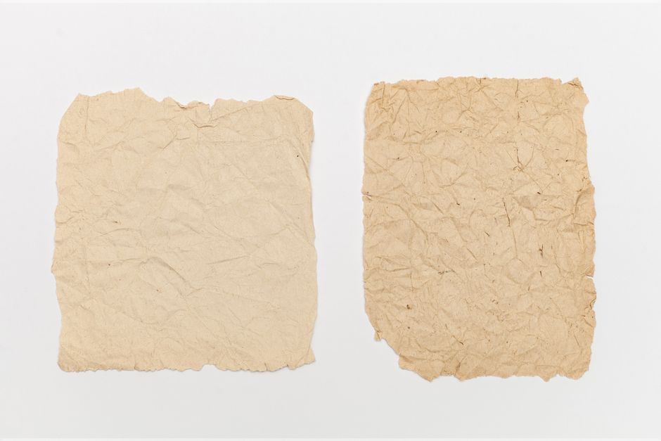 High-resolution image of two crumpled vintage papers on a plain surface, ideal for backgrounds.