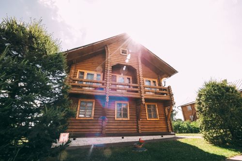 Free Capture of a sunlit wooden log cabin in a lush green setting, showcasing rustic charm. Stock Photo