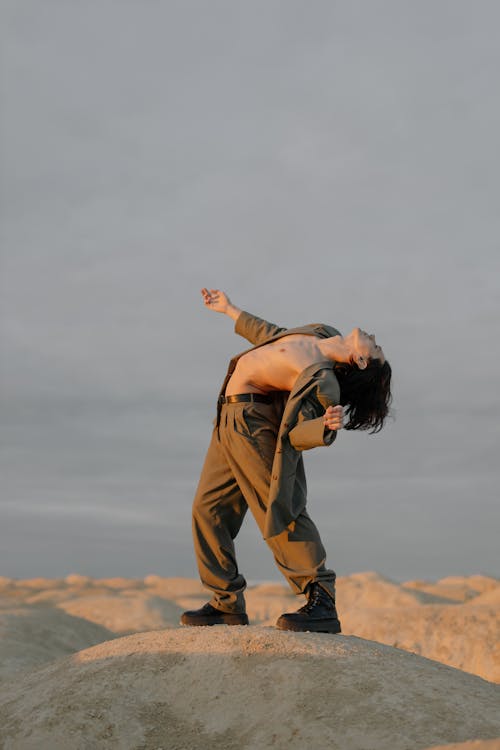 Woman in Brown Long Sleeve Shirt and Brown Pants Standing on Brown Field