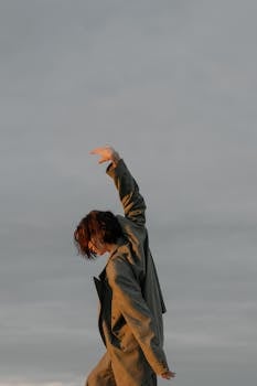 在平静多云的天空下，穿着西装的舞者优雅地在户外摆姿势，捕捉动作与风格