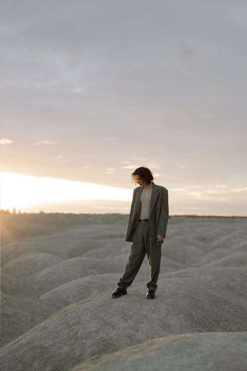 灰色の砂の上に立っている白いスーツの男