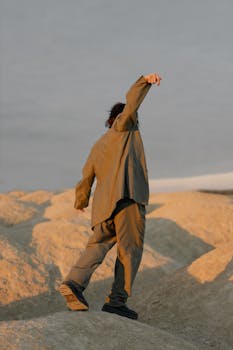 A man in a suit posing in a sandy desert setting at dawn.