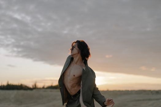 日落时分，一名赤裸上身的男子在户外拍摄了一幅具有现代风格的戏剧性肖像