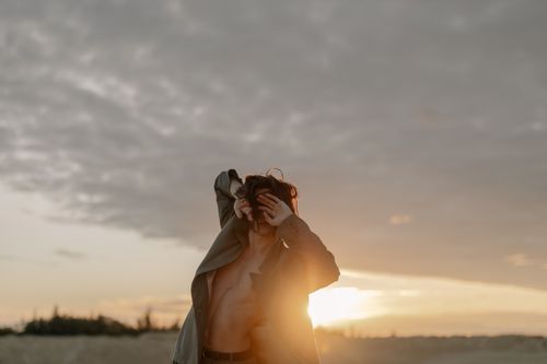 Free Fashion model poses outdoors at sunset, blending with the natural beauty and warm light. Stock Photo