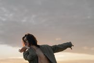 日落时分，男舞者在户外表演当代舞蹈，展示动作与表情