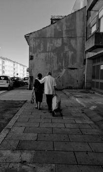 Black and white photo of senior couple walking together on a city sidewalk.