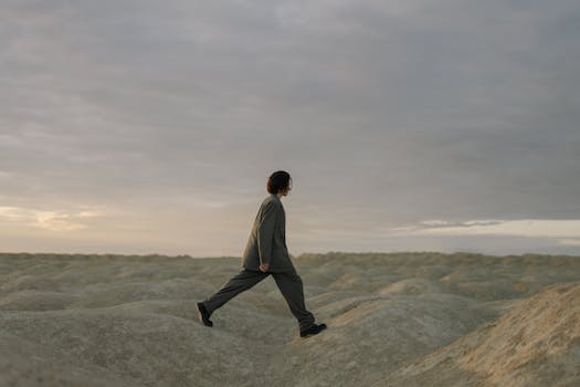 Man in a suit walking across a desert landscape at sunrise, showcasing a minimalist style with ample copy space.