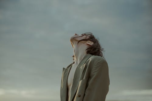 Woman in Beige Coat Standing Under White Sky