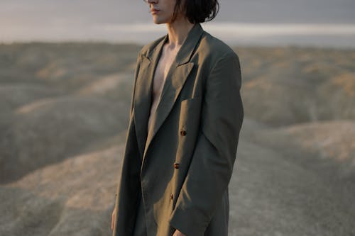 Woman in Brown Coat Standing on Gray Sand