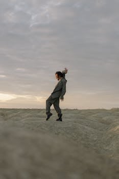 A lone dancer poses dramatically in a desert wearing a stylish suit, embracing minimalism in nature.