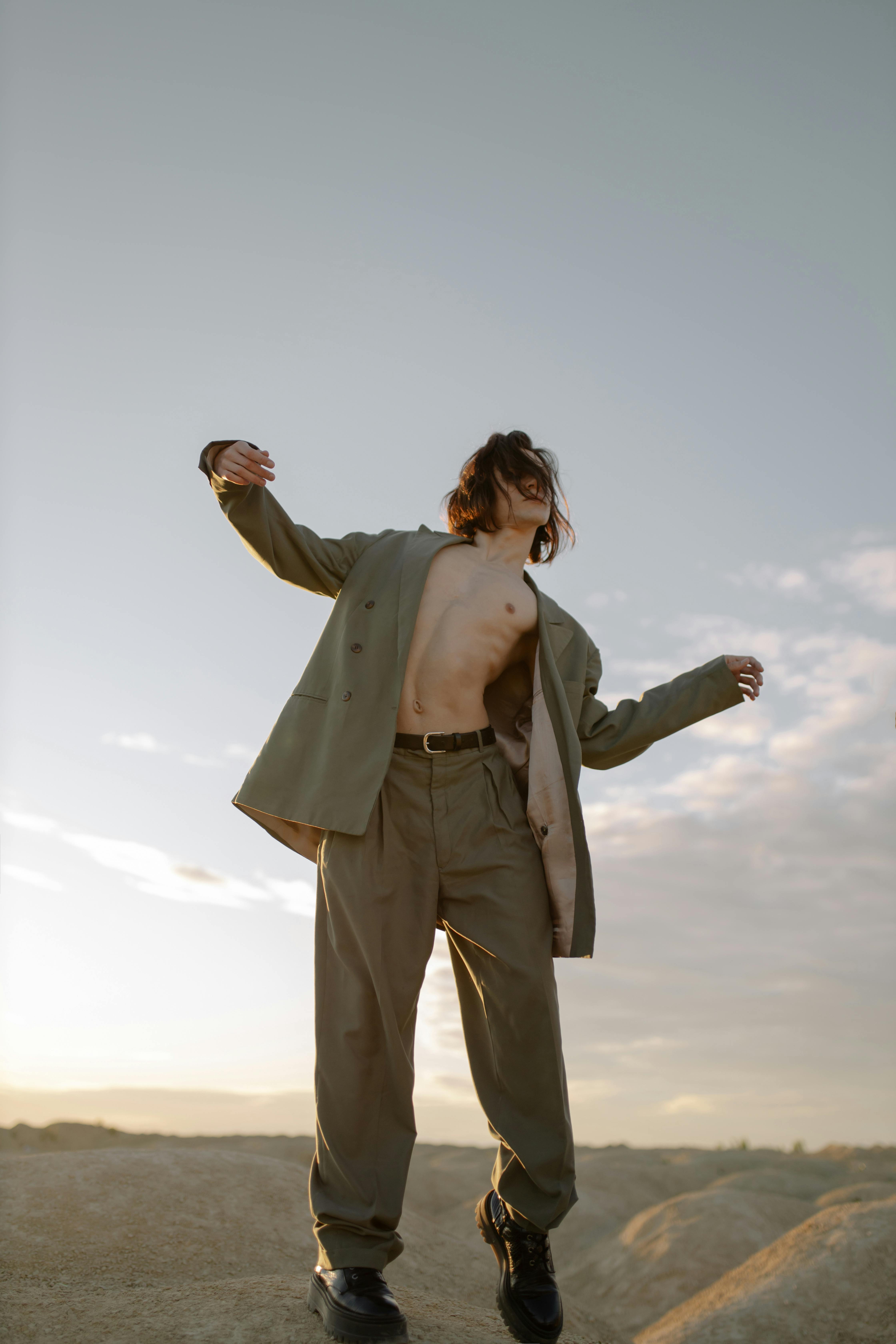A man joyfully embracing freedom outdoors in a stylish suit under a clear sky.