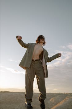 一个穿着时尚西装的男人，在晴朗的天空下快乐地拥抱自由