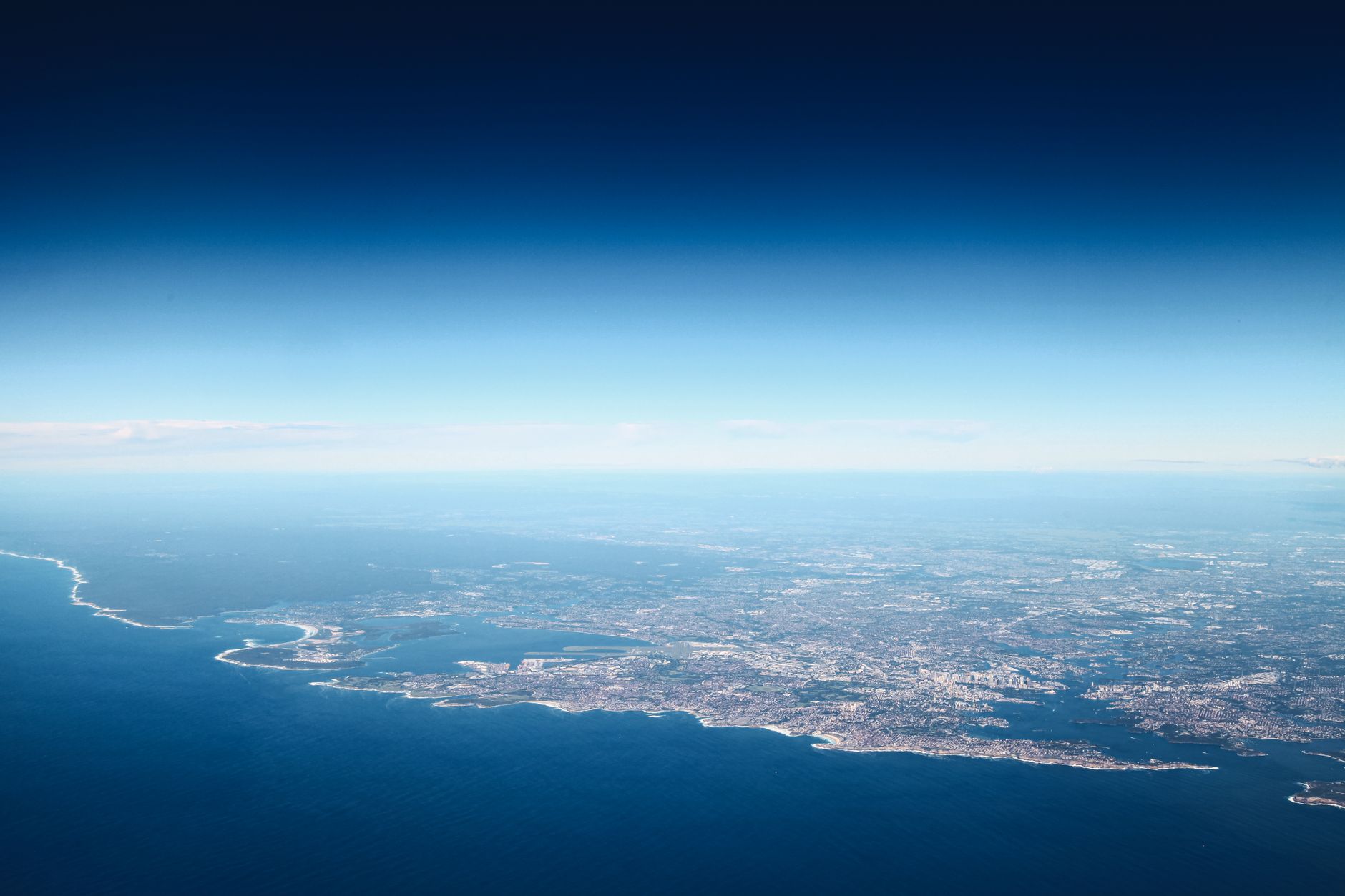 Aerial view of blue ocean with coastal town under colorful shiny sky in daylight