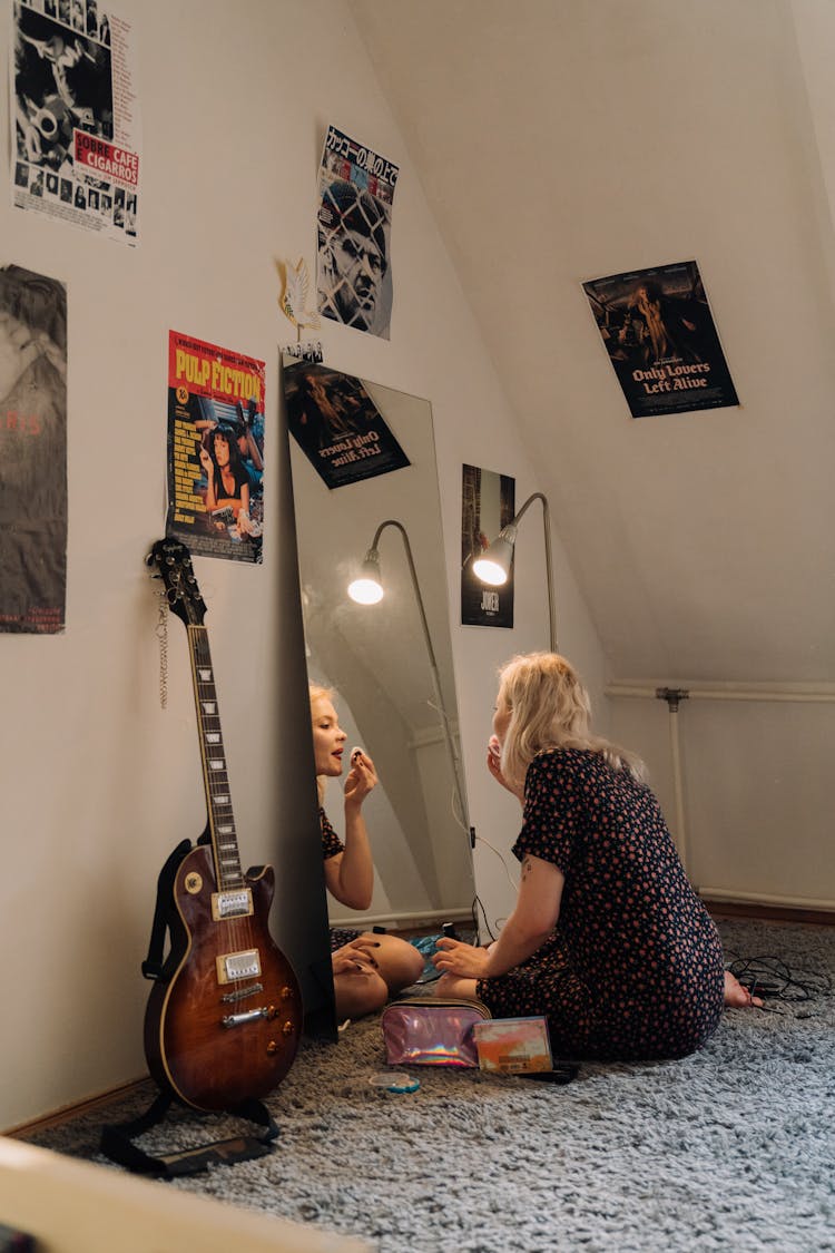 A Young Woman Putting On Makeup While Sitting On The Floor