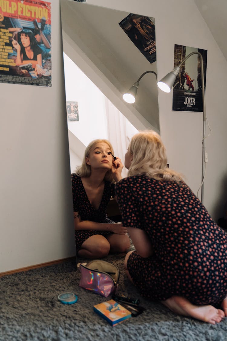 A Young Woman Putting On Makeup While Kneeling On The Floor