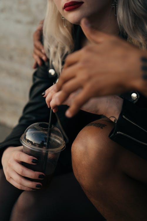 Person Holding Clear Plastic Cup with Black Straw