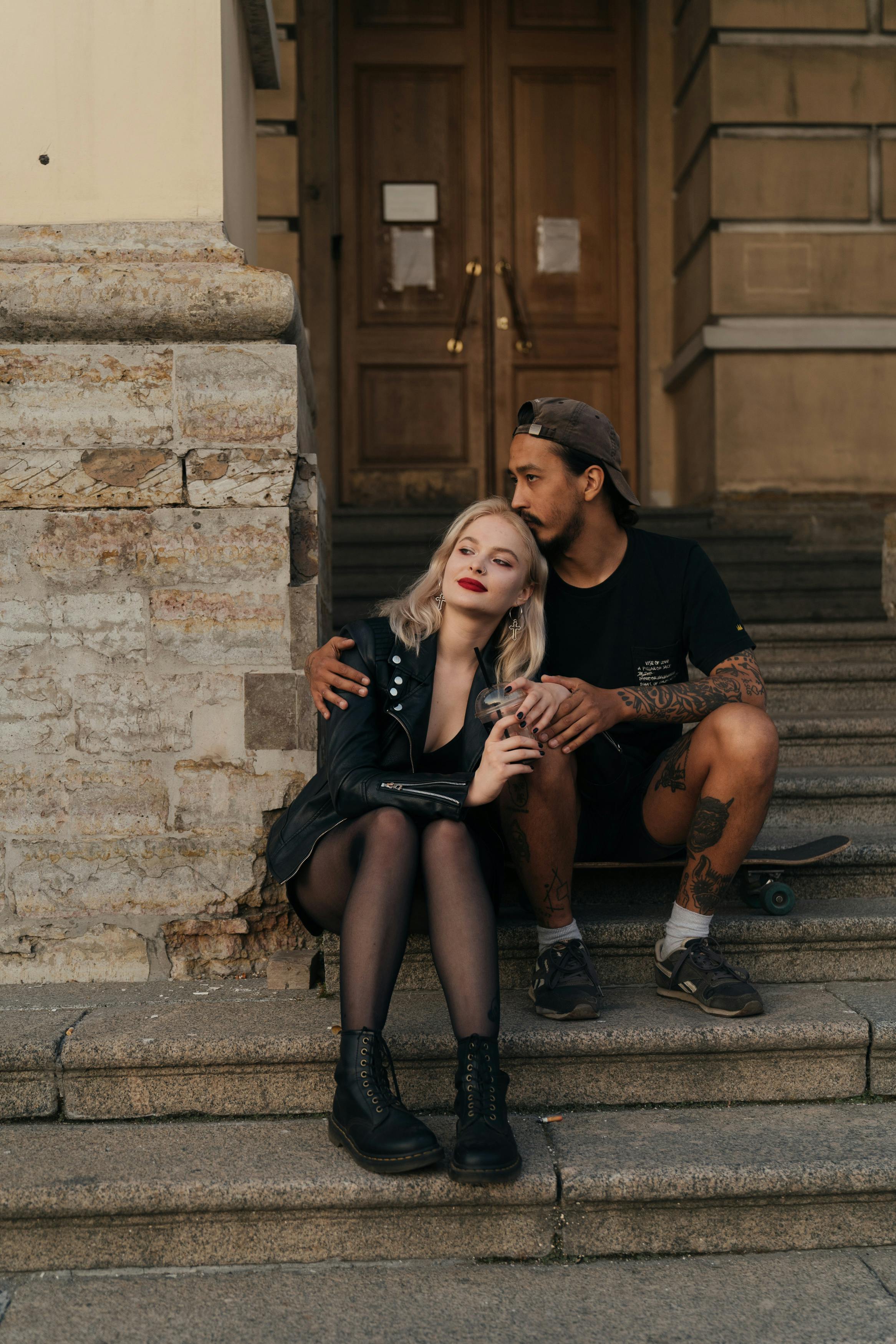 A couple sitting on outdoor stone steps, sharing an intimate moment and embrace.