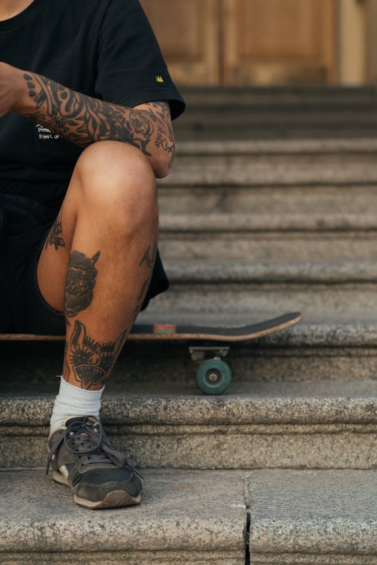 Man In Black Shirt Sitting On Skateboard