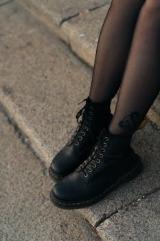 混凝土台阶上，黑色靴子和紧身裤的特写镜头非常适合时尚主题的构图