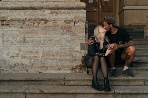 Couple Sitting on Concrete Stairs While Kissing