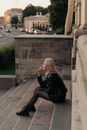 Woman in Black Leather Jacket Sitting on Gray Concrete Stairs