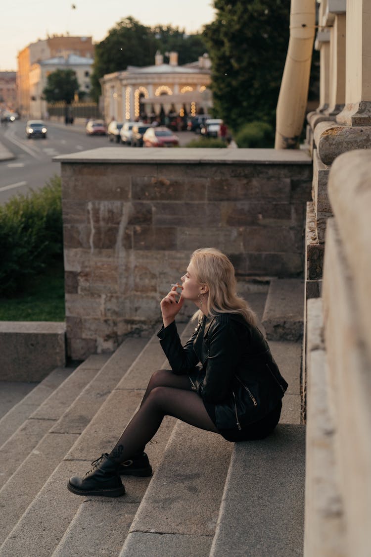 Woman In Black Leather Jacket Sitting On Gray Concrete Stairs