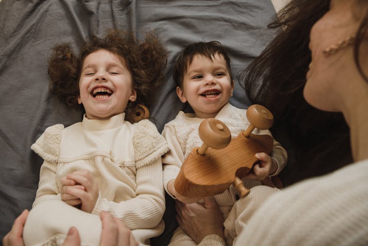 Little Boy And Girl Lying On Bed Laughing