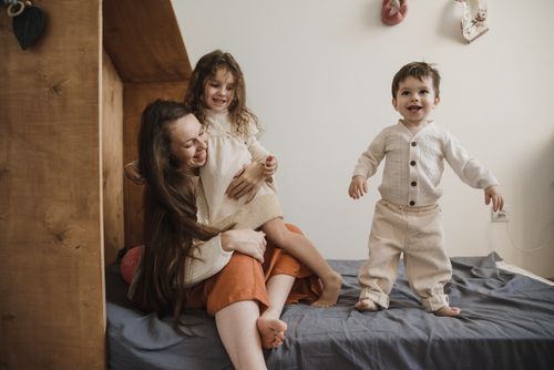Free A joyful mother spending quality time with her children on a bed, creating precious memories. Stock Photo