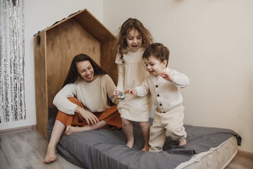 Woman Sitting on Bed Playing with Children