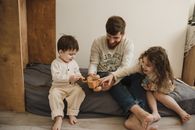 孩子们和父亲在室内舒适的床上玩着木制玩具