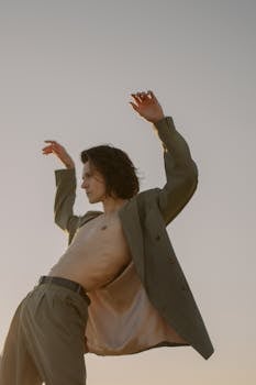 A shirtless male model dances under the clear sky of a vast desert scene.