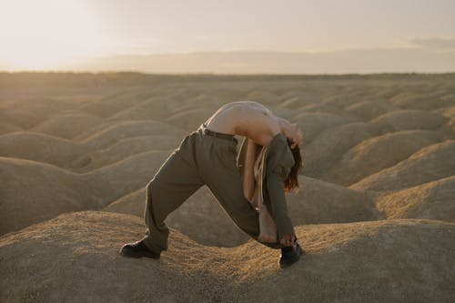 Man in Gray Hoodie and Brown Pants Sitting on Brown Sand