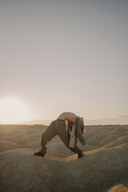 Man in Gray Long Sleeve Shirt and Black Pants Sitting on Brown Rock