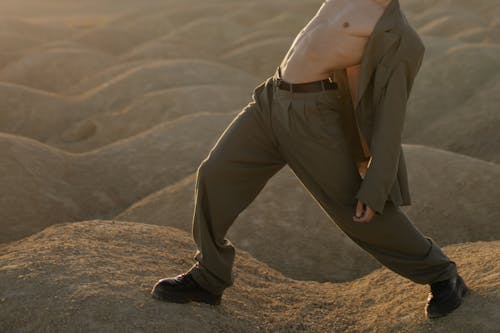 Man in White Shirt and Brown Pants Sitting on Brown Sand