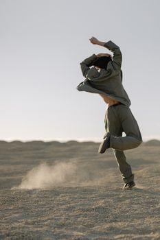 A man performing contemporary dance on a sandy desert landscape, capturing movement and grace.