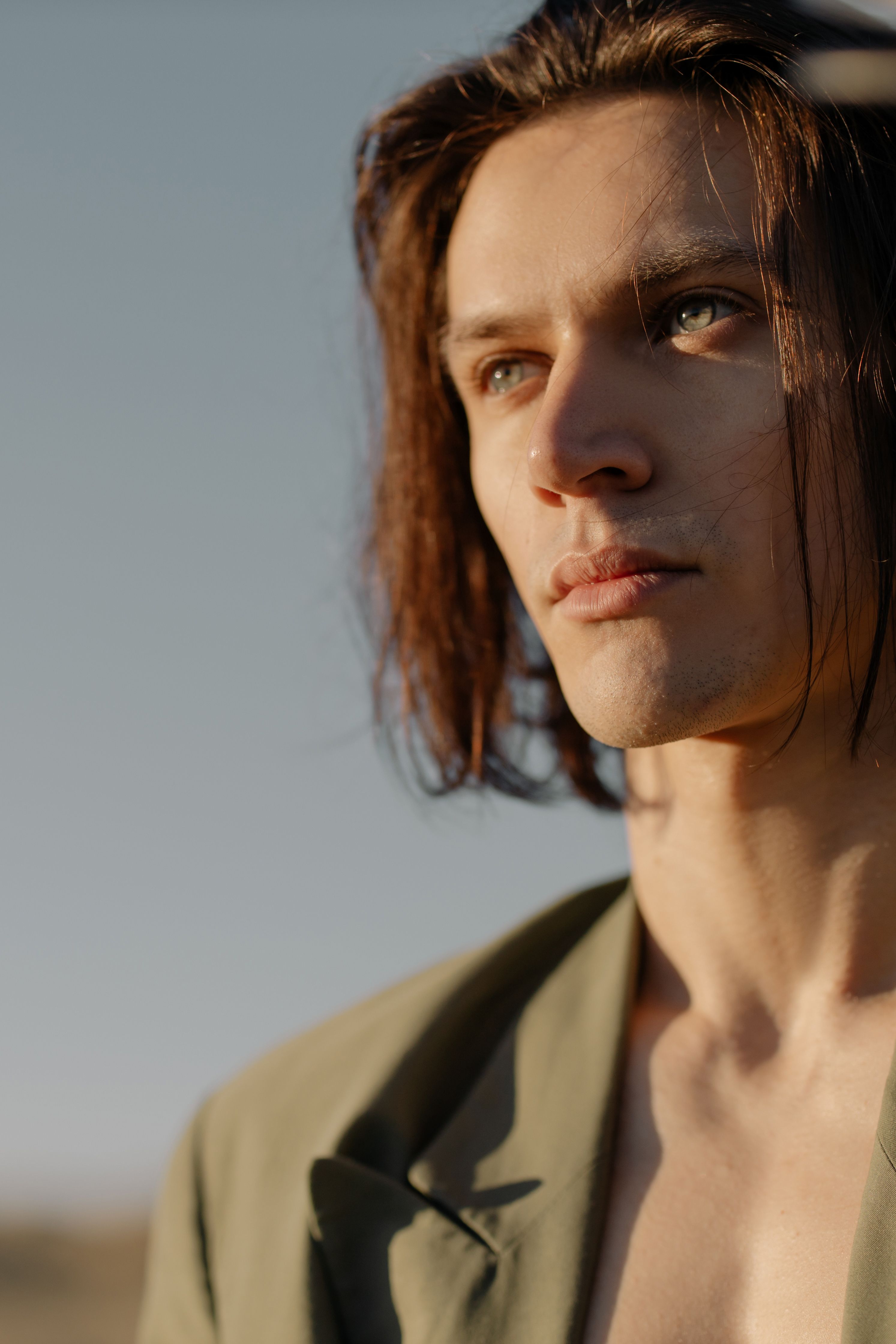 Close-up portrait of a young man with long hair and contemplative expression.