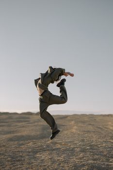 A dancer in mid-air leap on a desert landscape, showcasing contemporary dance and movement.