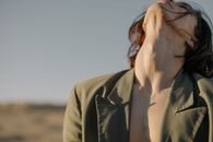 柔和的日光下，一个穿着绿色外套的人的无脸户外肖像