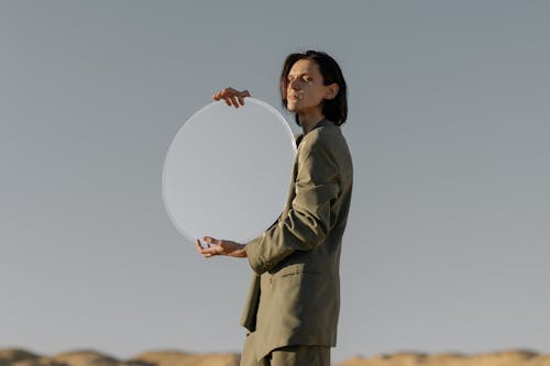 Woman in Gray Coat Holding White Round Ornament