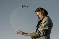 一个在户外沉思的人，正拿着一面圆镜探索光线和反射