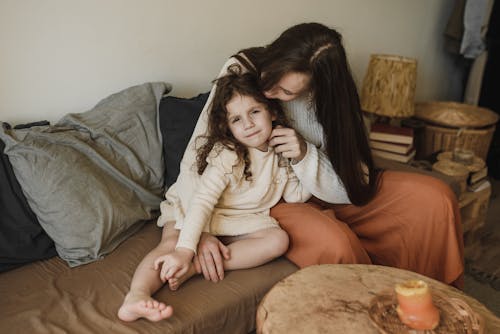 Mother and Daughter Sitting on Brown Sofa
