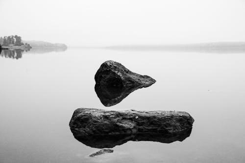 Grayscale Photo of Rocks on the Water