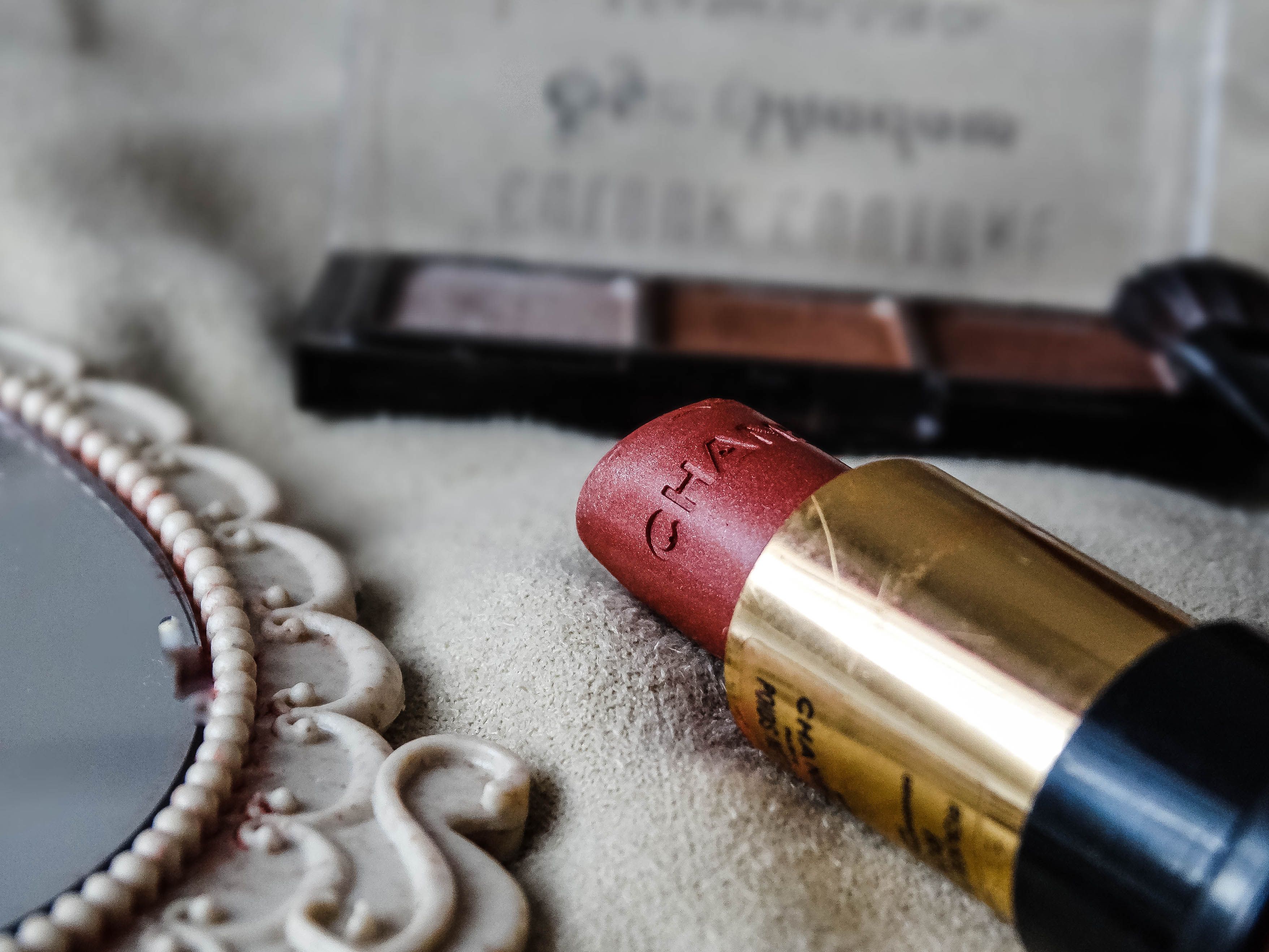 Lipstick beside a shadow palette on stone, the sort of practical vanity scene where nostalgia has to become habit.